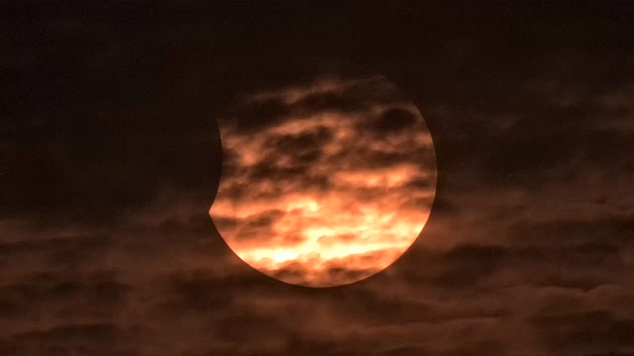Stage 5 of 5 · Final phase — the partially eclipsed Sun setting through cloud over Southport
